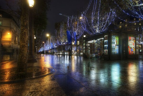 A night city with wet asphalt after rain, in which the lights of shop windows, windows and lanterns are reflected