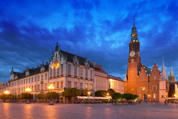 Wieczorne miasto skąpane w złocie świateł na tle błękitnego zachmurzonego nieba