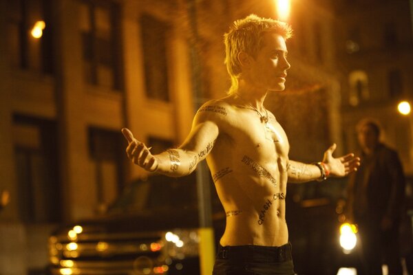 Jared Leto with a naked torso on the background of a building