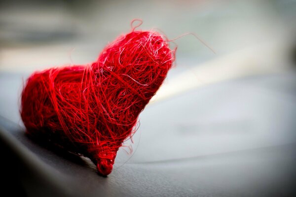 Dulce corazón, tejido de hilos rojos, sobre un fondo gris