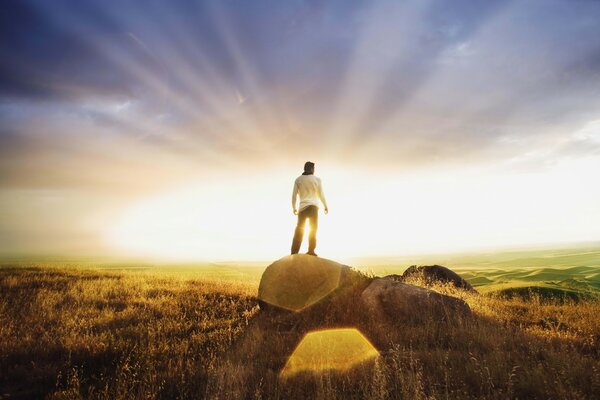 A man stands on a stone in the sunset rays