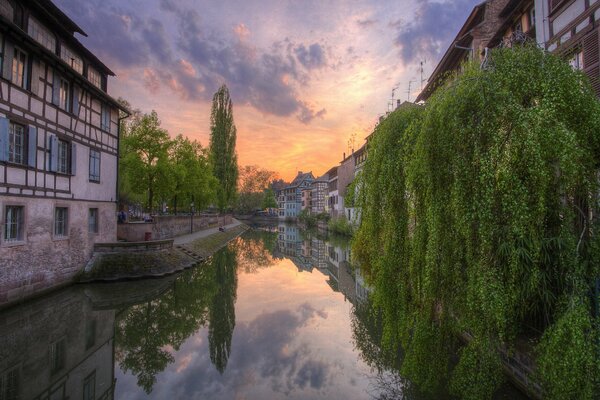 Beautiful view of the canal . Clouds are like airbags . The houses are covered with trees