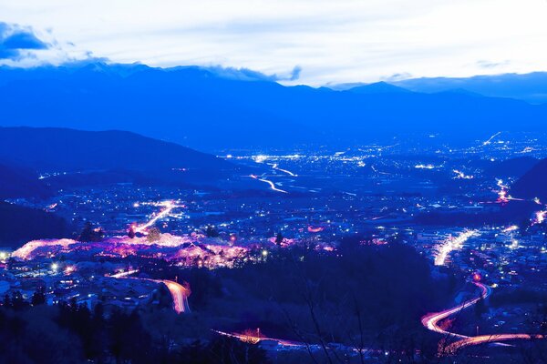 Nubes sobre un camino nocturno iluminado por luces en las montañas