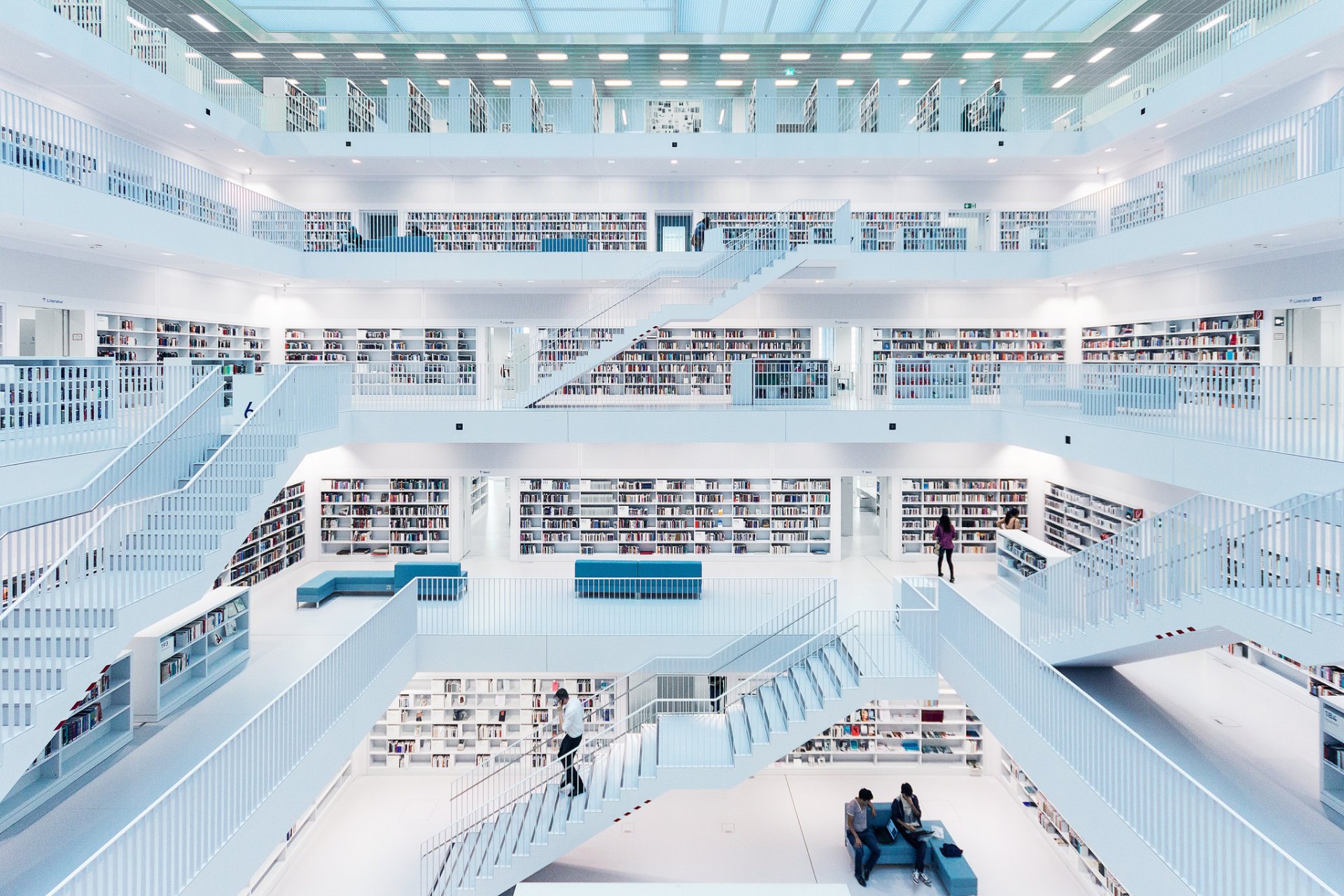 biblioteca libros escaleras personas sofá