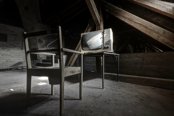 Dusty TV and a chair in the attic