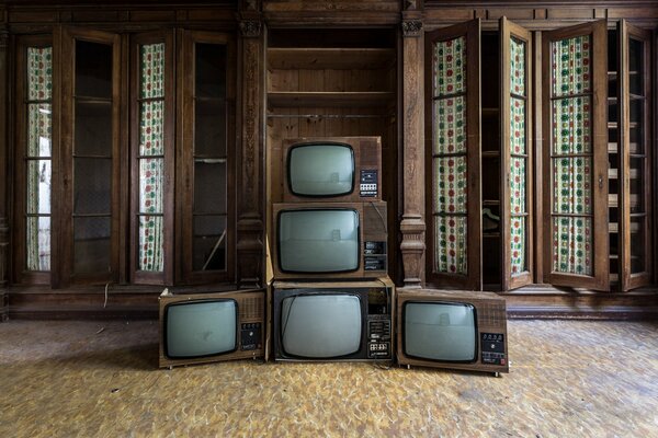 Pyramide de vieux téléviseurs sur fond d armoires en bois