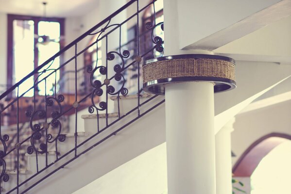 Openwork metal staircase and white column in the house