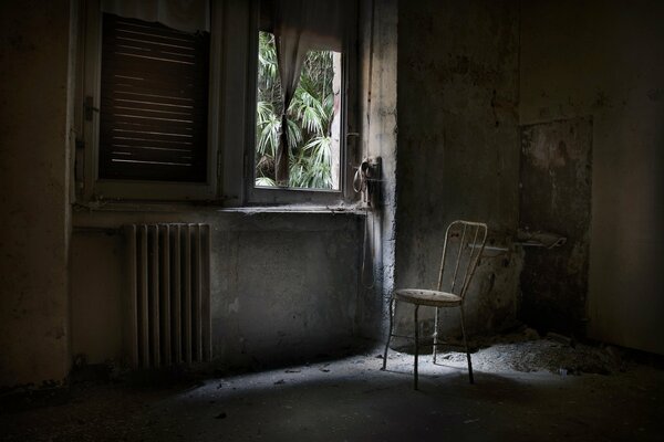 A dark room with a window and a chair