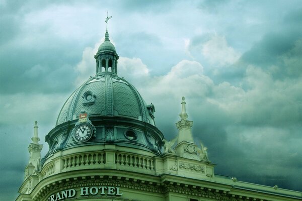 Clock on the roof of a building in the clouds