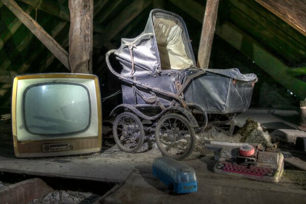 Alter Fernseher und Kinderwagen auf dem Dachboden