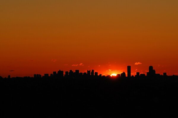 Silueta de una gran ciudad en el fondo de una puesta de sol roja