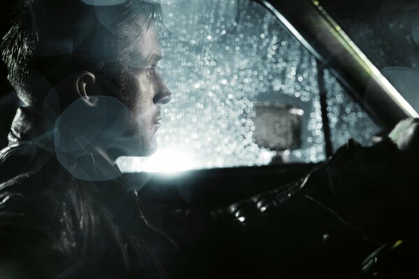 Homme dans la voiture la nuit et sous la pluie