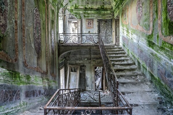 Verlassenes Gebäude mit Moos an den Wänden und einer Treppe