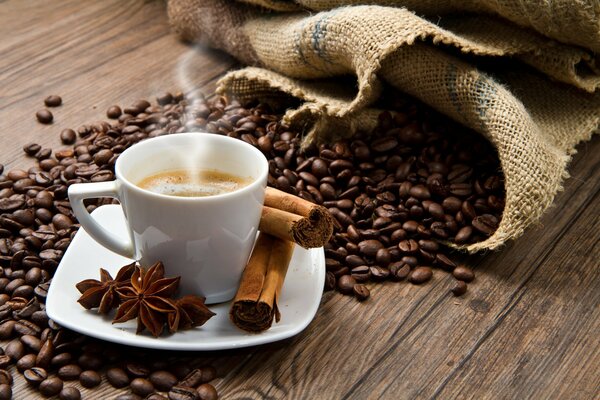 A cup of coffee with cinnamon on the background of coffee beans