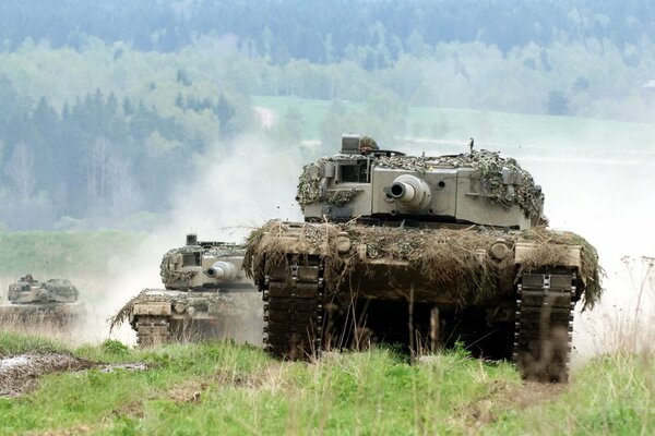 Several massive tanks are making their way forward through the field