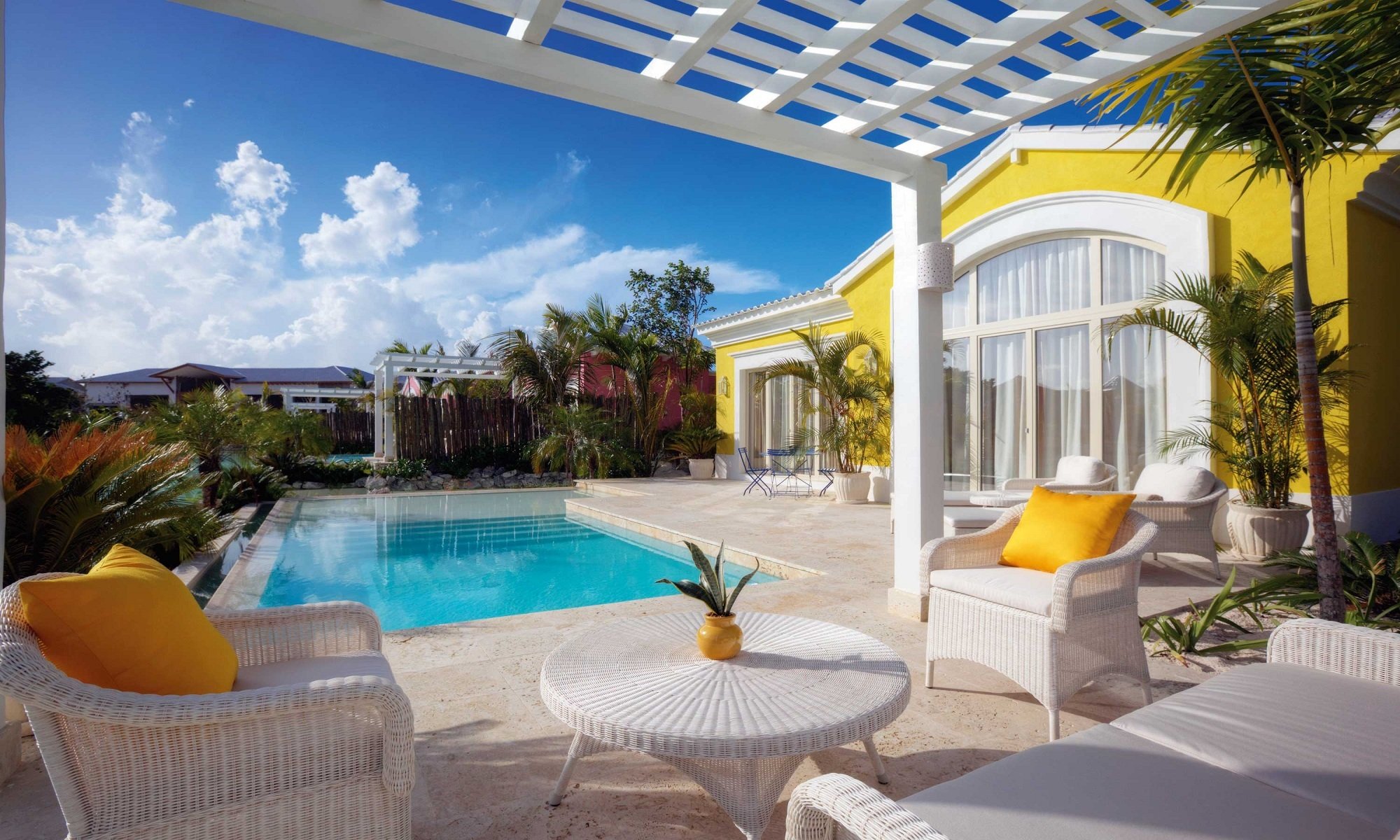 villa piscine chaises table plantes ciel nuages