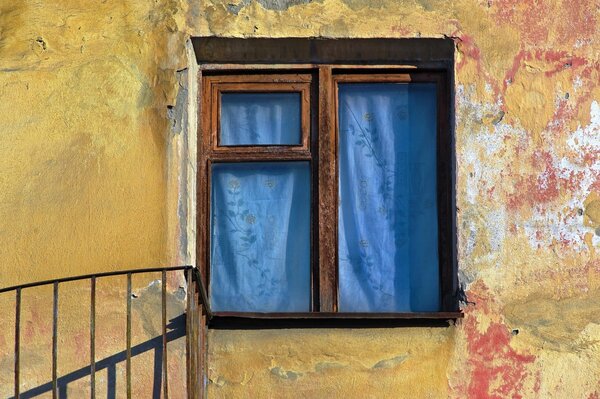 Gelbe Wand mit Holzvorhangfenster mit blauem Stoff