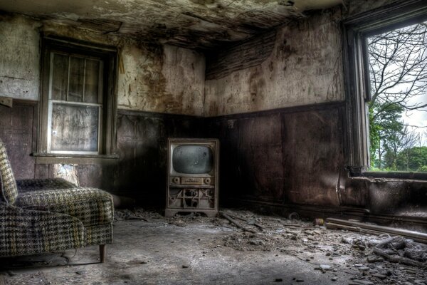 Una habitación desordenada y abandonada con una silla y un televisor