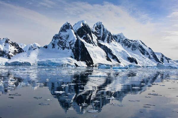 Reflejo de rocas nevadas en el agua