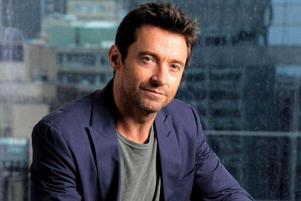 Hugh Jackman mit lila Jacke auf Fensterhintergrund