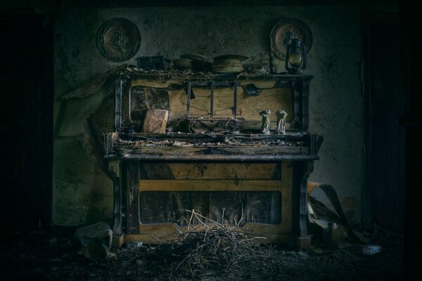 Chambre avec un vieux piano démonté et des statuettes dessus