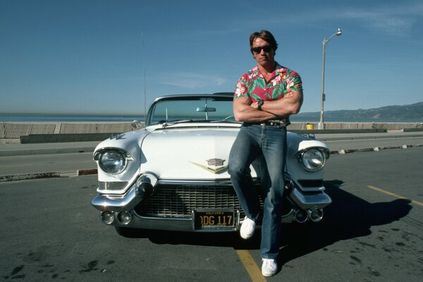 Young Arnold Schwarzenegger on the background of a car