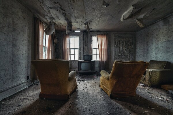 An abandoned room with armchairs and TV sets