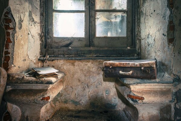 A suitcase in an old room on the background of a window