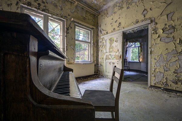 Habitación abandonada con una silla cerca del piano