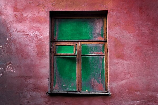 A red wall with an old wooden window