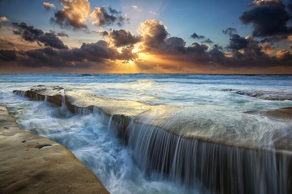 Sonne hinter Wolken, Meer und Wasserfall