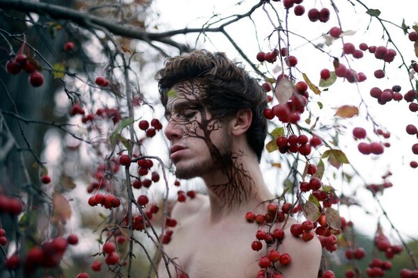 Cara linda de un hombre contra un árbol