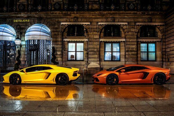 Two beautiful cars on the background of a night hotel