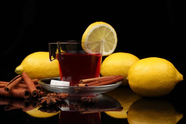 Tasse de thé avec des Citrons, des bâtonnets de cannelle, de la badiane et du raffinage