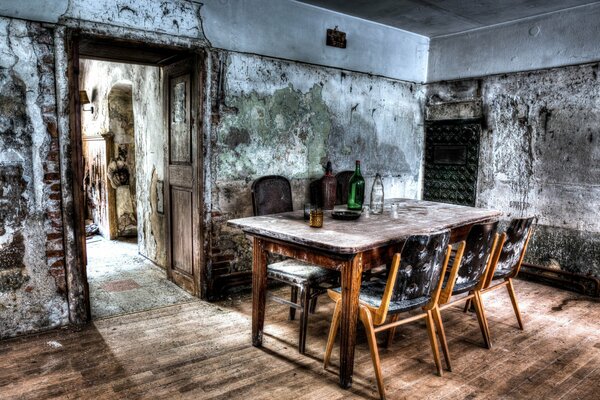 An abandoned dining room with a large table and chairs