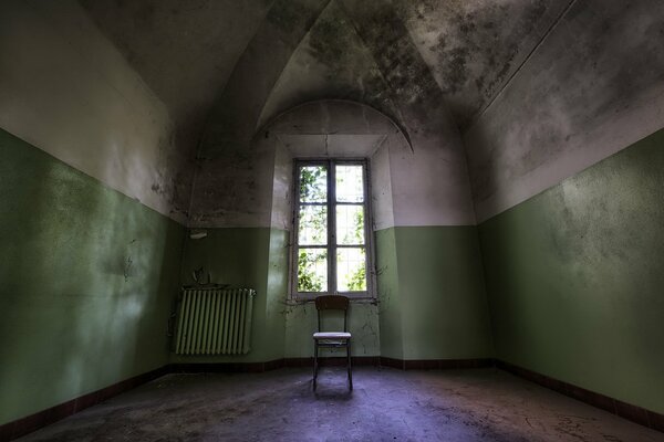 A gloomy room with one window and a chair