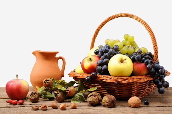 Still life with a basket of apples and grapes and a jug