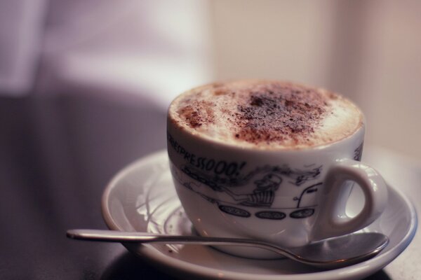 Cappuccino con espuma en una taza blanca sobre un fondo borroso