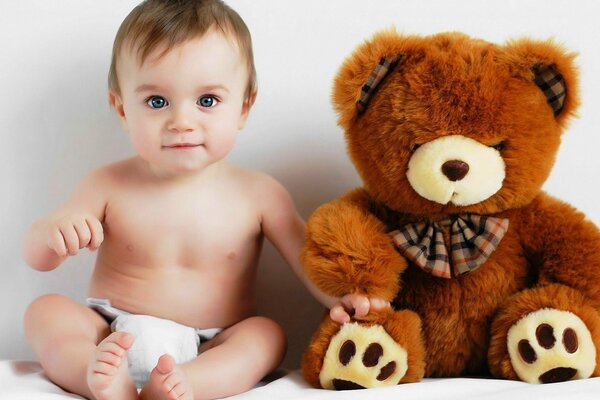 A small child sitting next to a bear