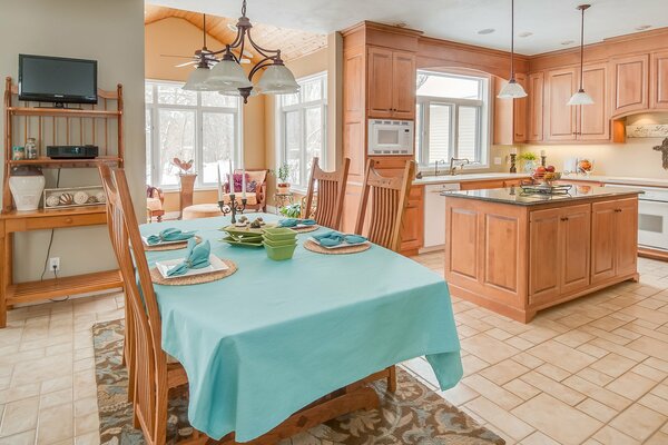 Cuisine en bois avec des chaises à haut dossier montées sur une table recouverte d une nappe turquoise