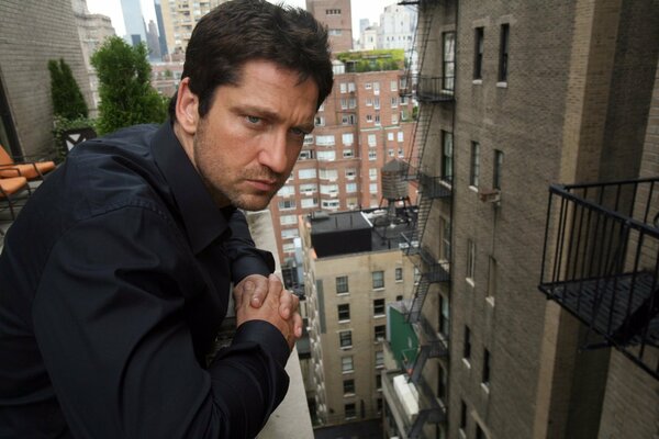 Gerard Butler on the balcony of a high-rise building