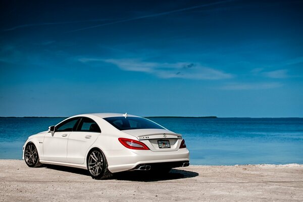 Weißer Mercedes auf dem Hintergrund von Meer und Sand