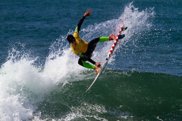 Surfing. Mann im Sprung auf einer Welle mit einem Brett