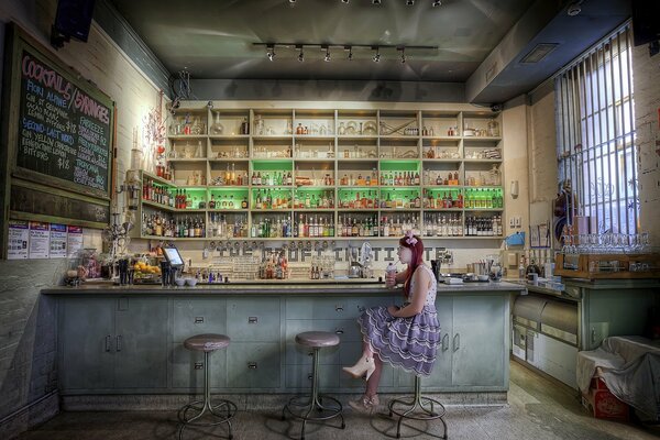 A girl drinks a cocktail at the bar