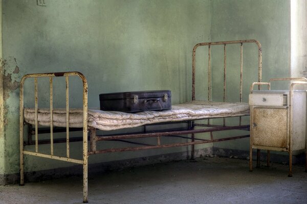 An old rusty bed with a suitcase