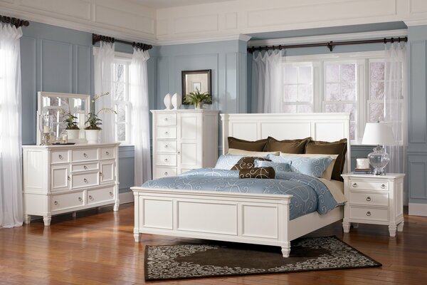 A bright room with a bed and white furniture