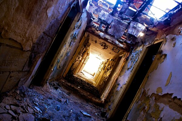 Ruin, dirt and light at the end of the tunnel. The roof of the hall fell . Peeling with an autonomous heater in the door