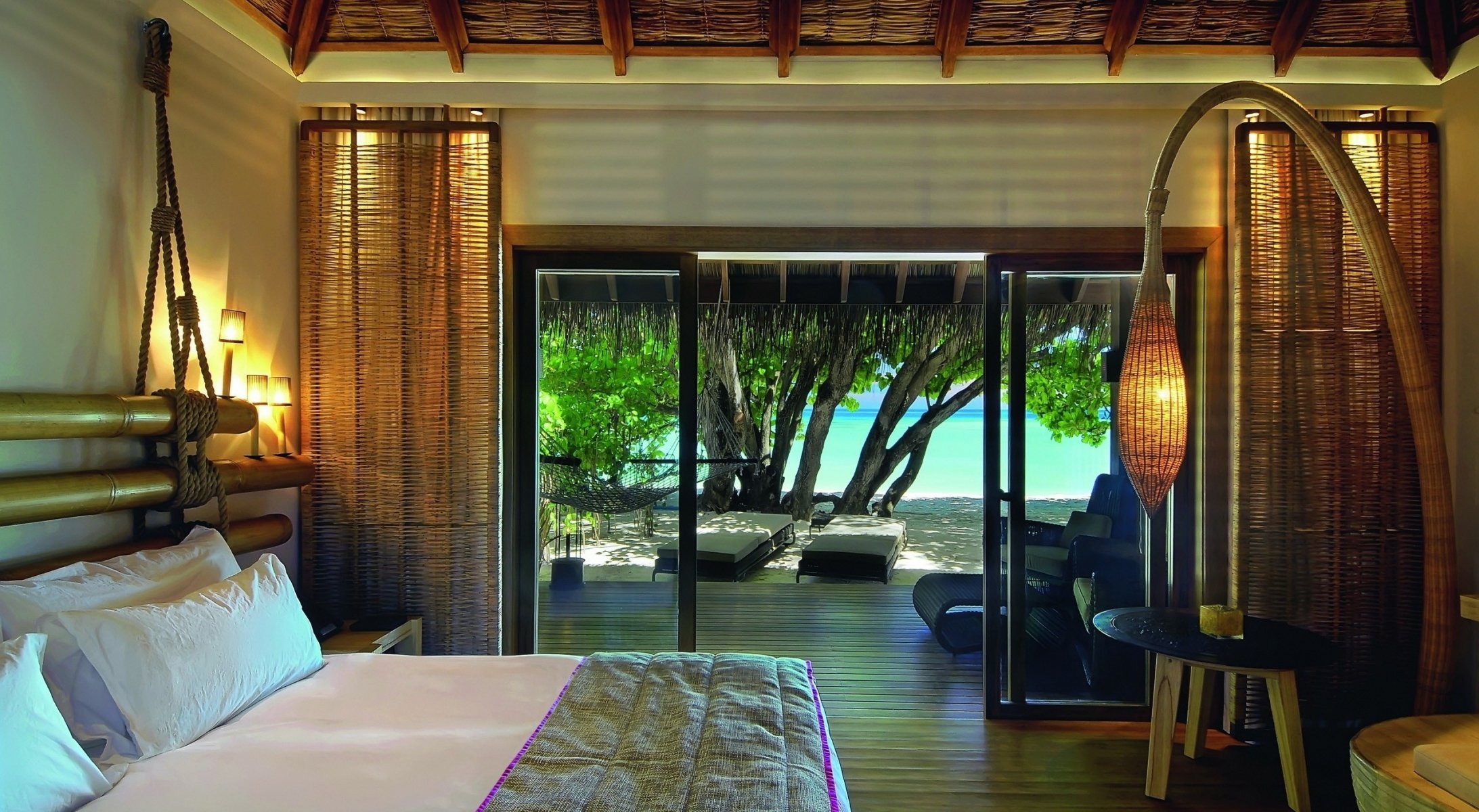 letto constance camera maldive moofushi resort vista spiaggia interno legno