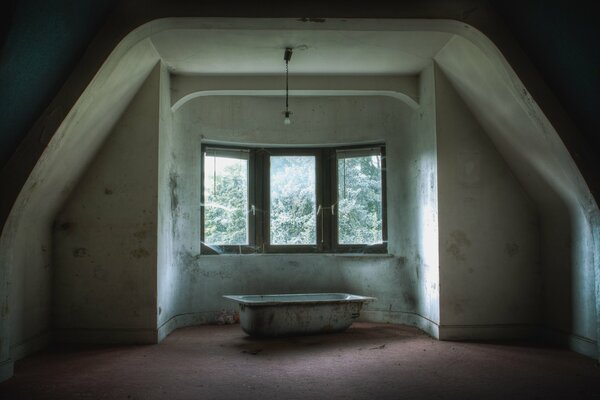 In an abandoned house, a bathtub stands by the window