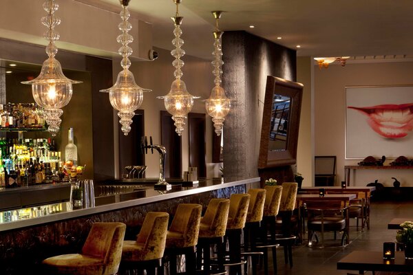 The interior of the restaurant s bar area with beautiful chandeliers and an original painting